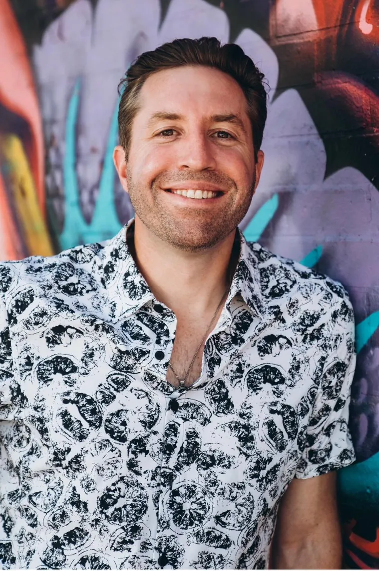 Rob Cressy, human-first AI coach and keynote speaker, smiling in front of a colorful mural